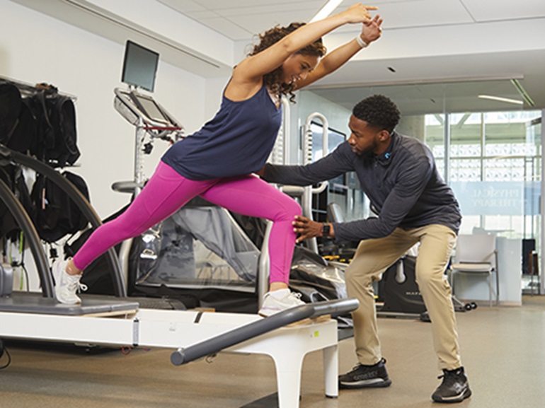 A male physical therapist working on stability exercises on a platform with a female patient. 