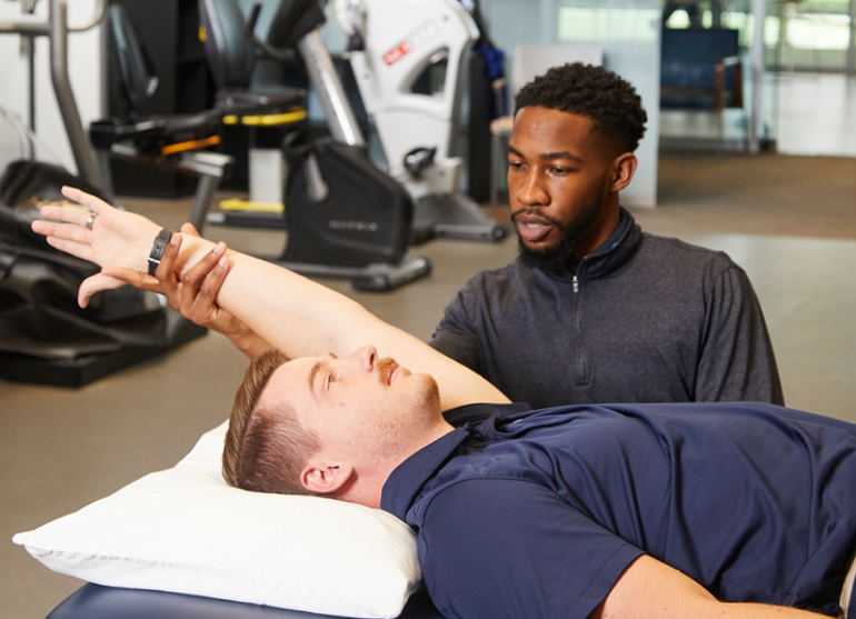 A male physical therapist stretching a man's arm for better range of motion. 
