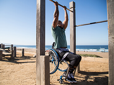 Leonard does a pull up on the beach while sitting in his wheelchair.